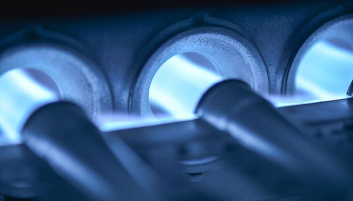 Close-up of blue-lit metal tubes and circular openings in a mechanical assembly.
