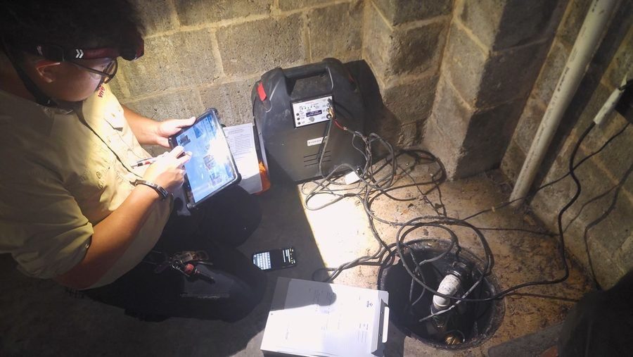 Plumber looking at camera screen during sewer line inspection.