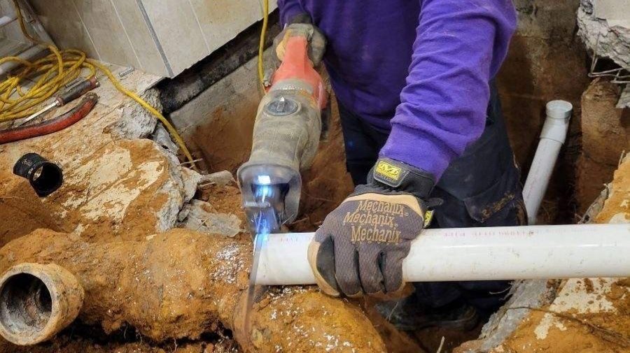 Plumber repairing a PVC pipe during residential plumbing service.